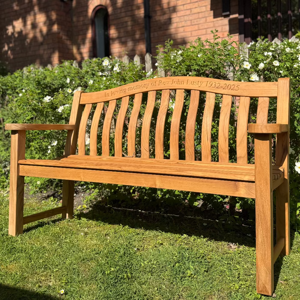 Wooden bench in a garden setting with a brick building in the background