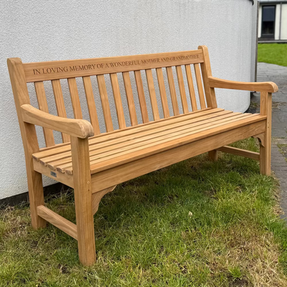 Wooden bench with engraved text in a garden setting